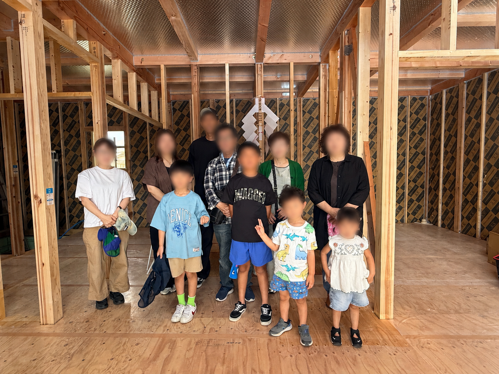  室内でのご家族集合写真 上棟した新築住宅の構造内部でご家族と記念撮影